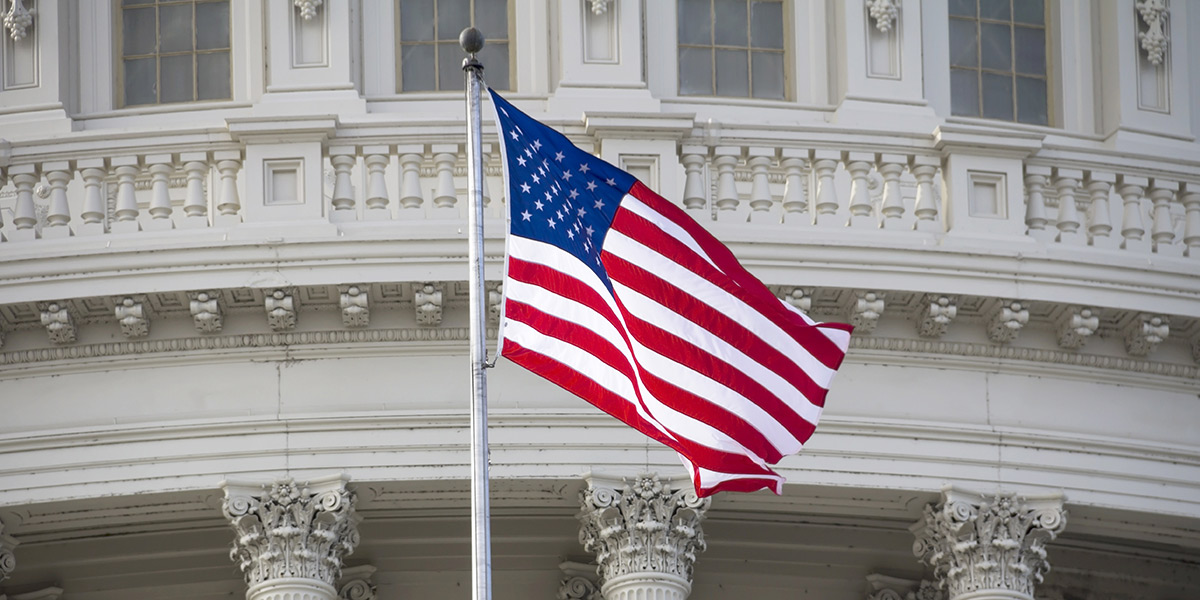 American flag waving in the wind in front of the Wisconsin capitol building