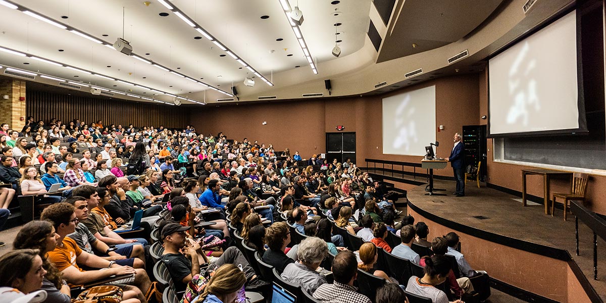 man giving presentation in front of full lecture hall