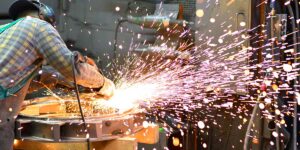 worker in safety clothing sanding metal and sparks fly out