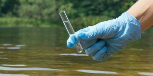 A man holding a vial of water that he got from the river.